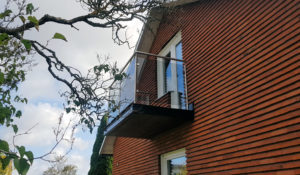 Rostfritt balkongräcke med rökfärgat glas.